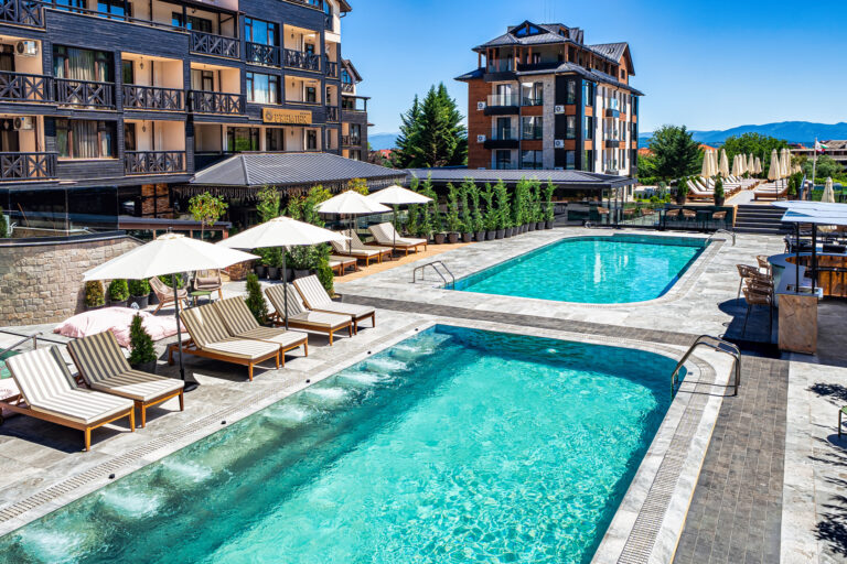 Outdoor pools and sun terrace with parasols at Premier Luxury Mountain Resort, Bansko