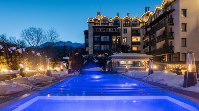 Illuminated outdoor pool at night at Premier Luxury Mountain Resort, Bansko