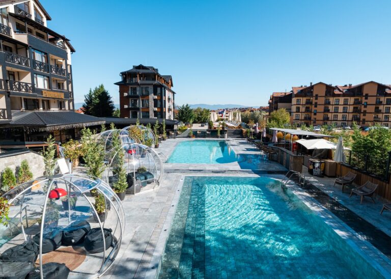 Glass igloos with lounge seating by the outdoor pool at Premier Luxury Mountain Resort, Bansko