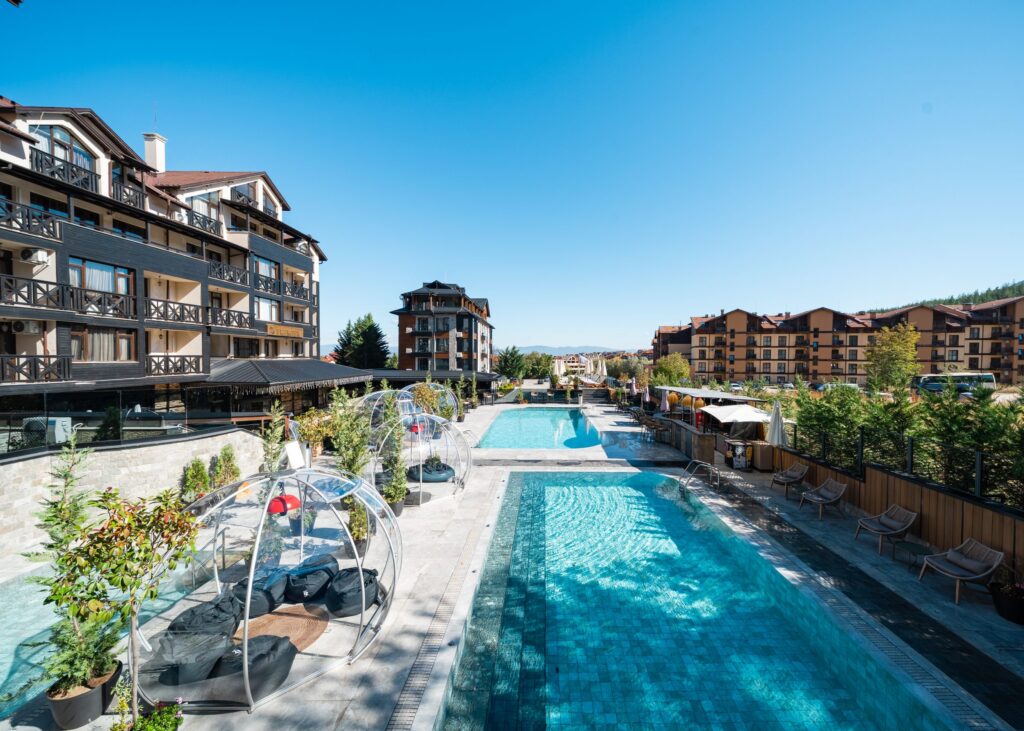 Outdoor pools with transparent igloos and the hotel building at Premier Luxury Mountain Resort, Bansko