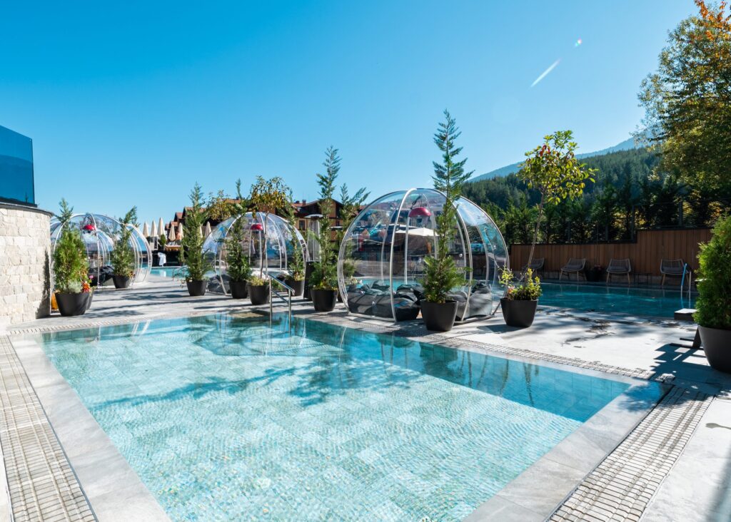 Outdoor pool with transparent igloos and autumn trees at Premier Luxury Mountain Resort, Bansko
