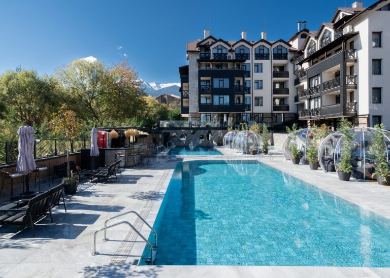 Large outdoor pool with igloos and the hotel facade at Premier Luxury Mountain Resort, Bansko
