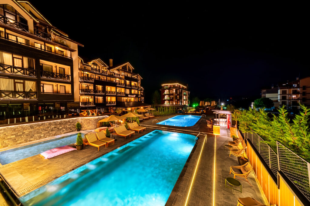Illuminated outdoor pool at night at Premier Luxury Mountain Resort, Bansko